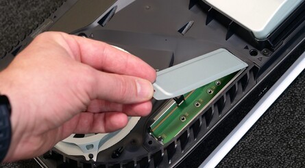 (Clockwise from top left) The SSD slot is located in the bottom-left corner of the console, as shown in this photo. Use a crosshead screwdriver to remove the screw, and note the fancy PlayStation symbols. Lift the metal plate away to reveal the SSD slot beneath.