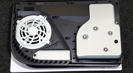 (Clockwise from top left) The SSD slot is located in the bottom-left corner of the console, as shown in this photo. Use a crosshead screwdriver to remove the screw, and note the fancy PlayStation symbols. Lift the metal plate away to reveal the SSD slot beneath.